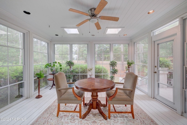 sunroom / solarium featuring ceiling fan, a skylight, wood ceiling, and plenty of natural light