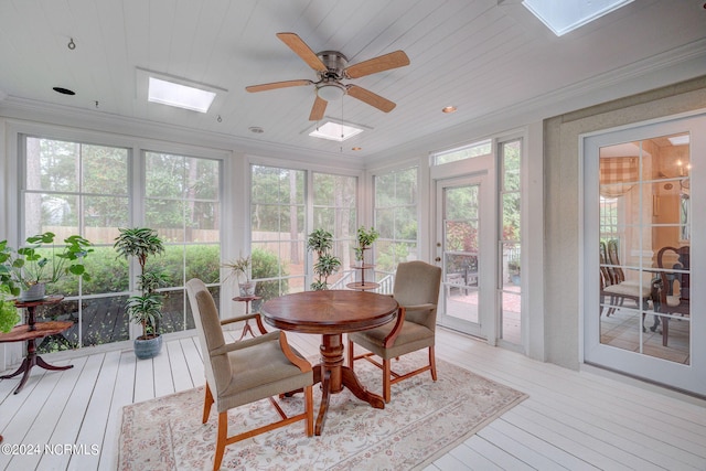 sunroom featuring wooden ceiling, ceiling fan, a skylight, and plenty of natural light