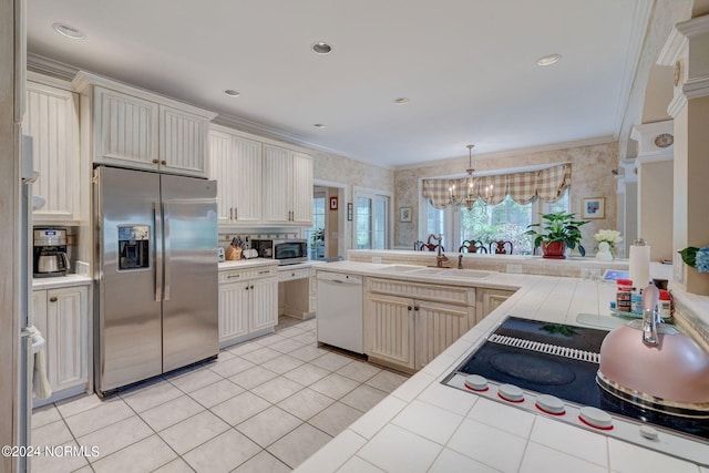 kitchen featuring tile counters, sink, an inviting chandelier, stainless steel appliances, and ornamental molding