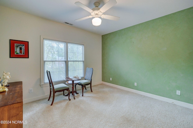 living area with light carpet and ceiling fan