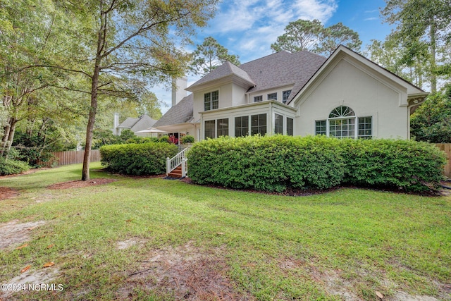 view of front of property featuring a sunroom and a front lawn