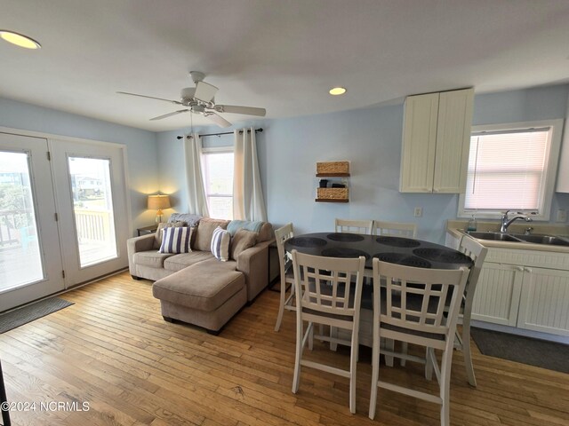 dining space featuring ceiling fan, light wood-type flooring, plenty of natural light, and sink