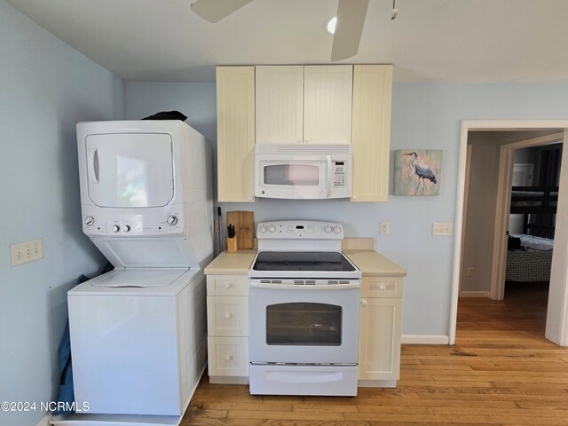 kitchen featuring light wood-type flooring, stacked washer / drying machine, and white appliances