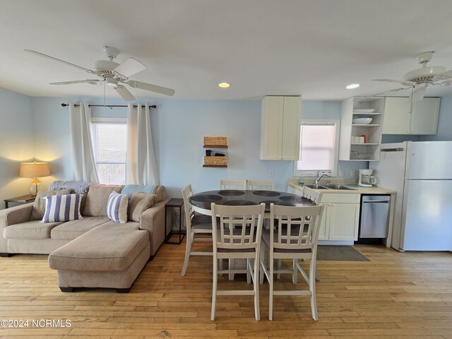 dining area featuring ceiling fan, sink, and light hardwood / wood-style flooring