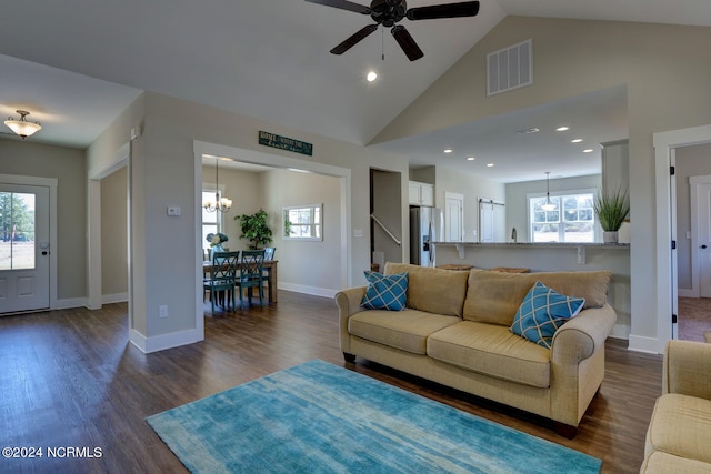 living room featuring dark hardwood / wood-style floors, ceiling fan with notable chandelier, and high vaulted ceiling