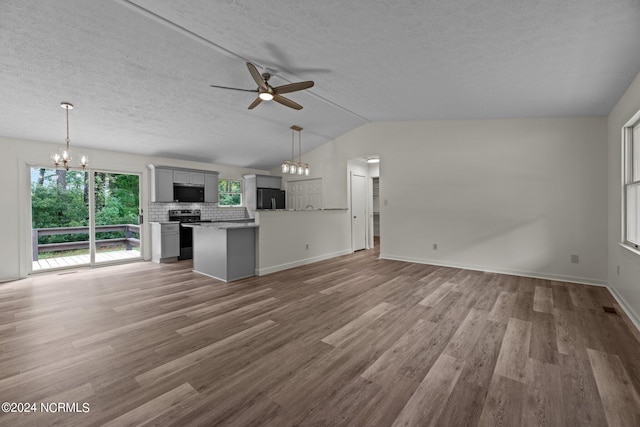 kitchen with gray cabinetry, vaulted ceiling, stainless steel appliances, ceiling fan with notable chandelier, and hardwood / wood-style floors