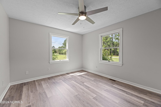 empty room featuring light hardwood / wood-style floors, ceiling fan, a healthy amount of sunlight, and a textured ceiling