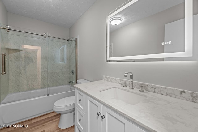 full bathroom with vanity, a textured ceiling, toilet, shower / bath combination with glass door, and hardwood / wood-style floors