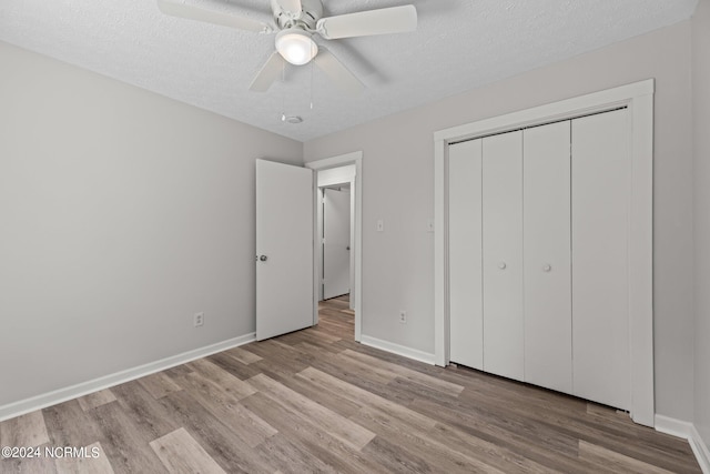 unfurnished bedroom with light hardwood / wood-style flooring, a closet, ceiling fan, and a textured ceiling