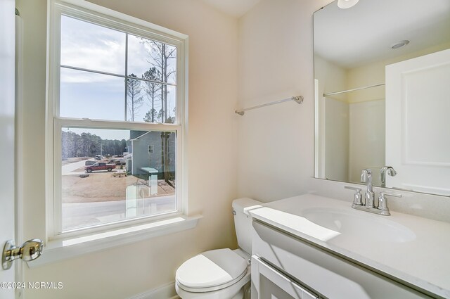 bathroom with walk in shower, vanity, and toilet