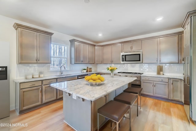 kitchen featuring stainless steel appliances, a breakfast bar, sink, and light hardwood / wood-style flooring