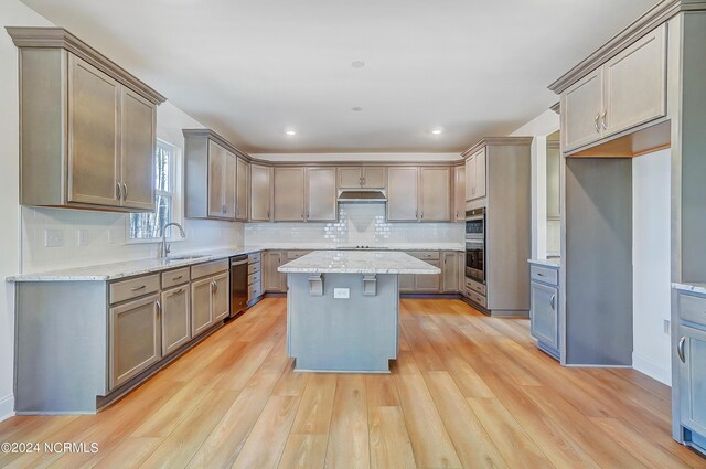 kitchen featuring light wood-type flooring, a center island, stainless steel appliances, and sink