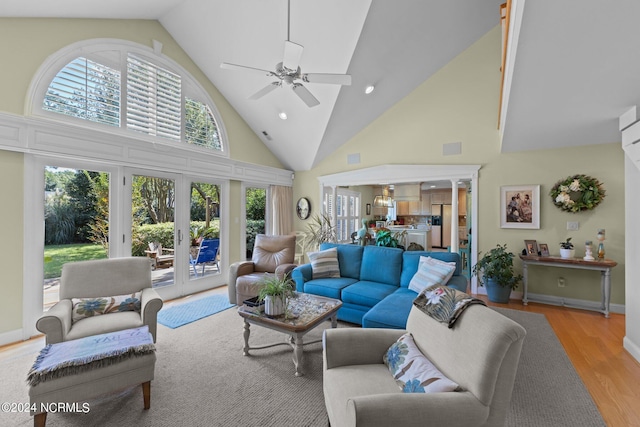 living room with light hardwood / wood-style floors, a towering ceiling, and ceiling fan