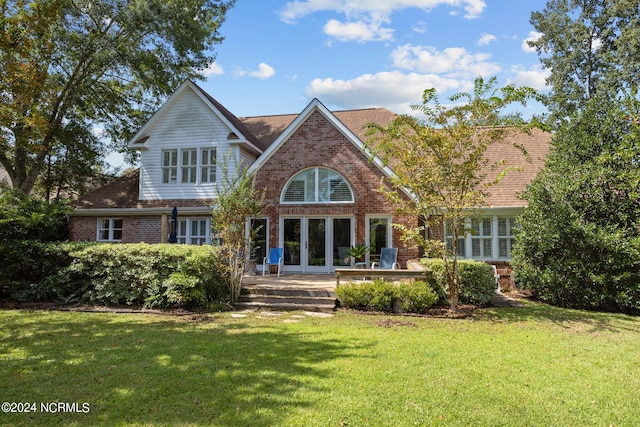 back of property with a lawn and french doors