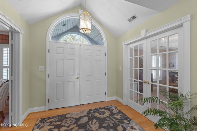 foyer with hardwood / wood-style flooring, lofted ceiling, french doors, and a healthy amount of sunlight