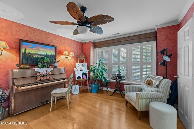 living area with light wood-type flooring, ceiling fan, and ornamental molding