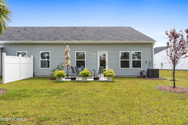 rear view of house featuring roof with shingles, a patio, a lawn, central AC, and fence