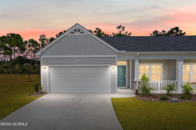 view of front of property with driveway, an attached garage, a front lawn, and a porch