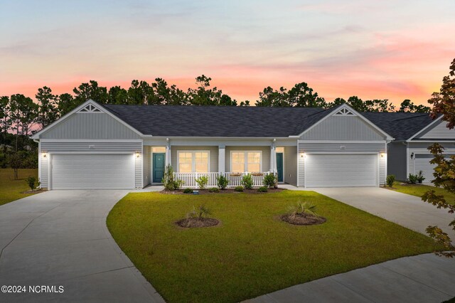 ranch-style home featuring covered porch, concrete driveway, a lawn, and a garage