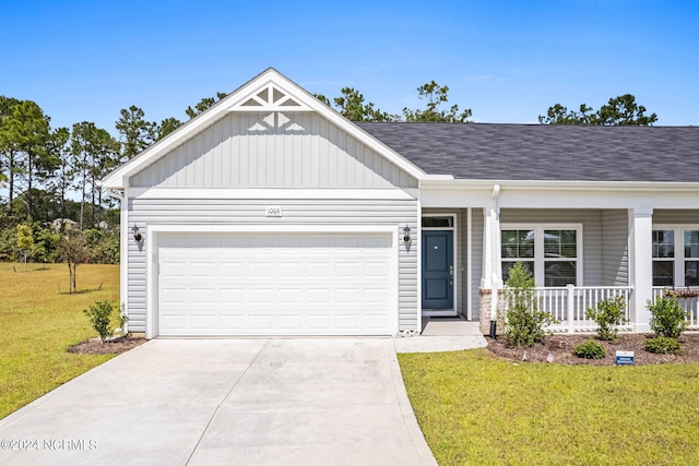 view of front of home featuring a front lawn, covered porch, and a garage