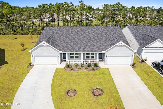 ranch-style house featuring a shingled roof, a front yard, covered porch, and driveway