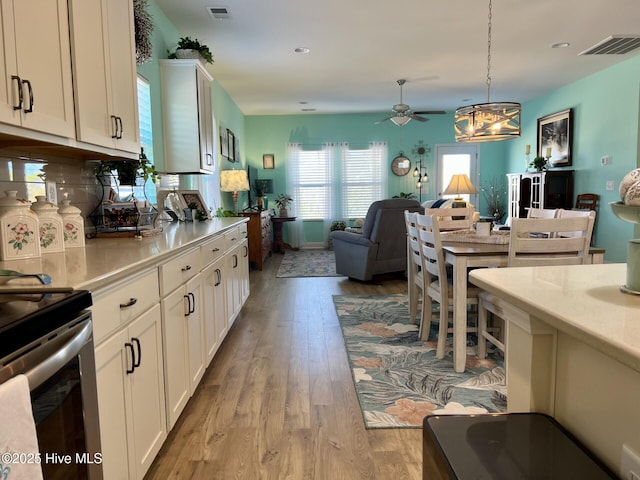 kitchen with white cabinetry, light wood-style floors, open floor plan, light countertops, and pendant lighting