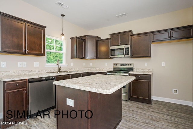 kitchen with wood-type flooring, sink, pendant lighting, and stainless steel appliances