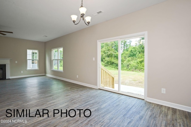 unfurnished living room featuring ceiling fan with notable chandelier and dark wood-type flooring