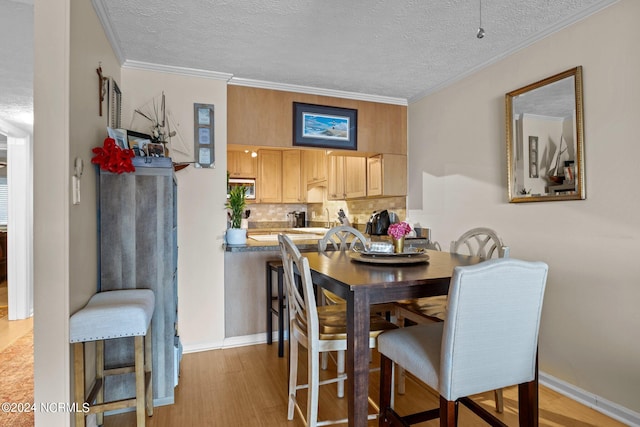 dining space featuring a textured ceiling, ornamental molding, and light hardwood / wood-style flooring