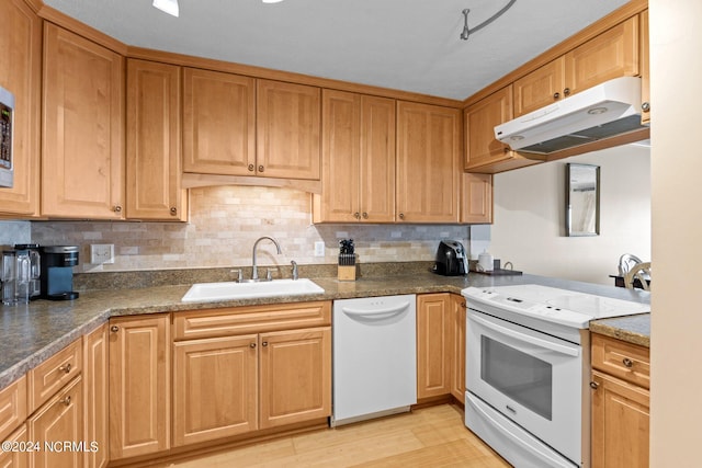 kitchen featuring light wood-type flooring, sink, decorative backsplash, white appliances, and dark stone countertops