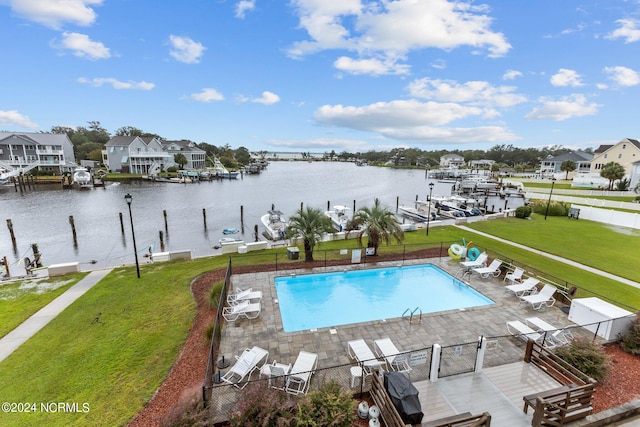 view of pool with a patio, a yard, and a water view