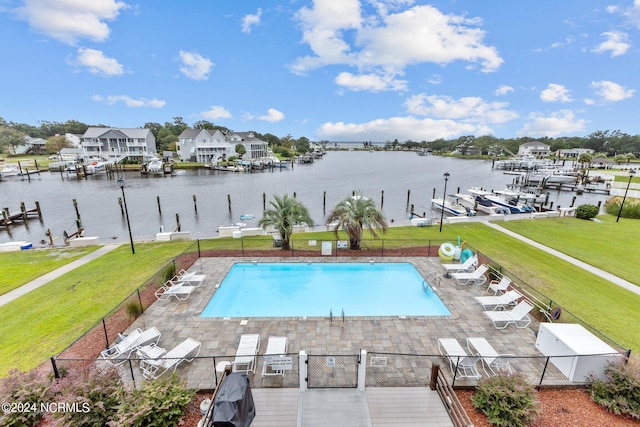 view of pool featuring a patio, a water view, and a lawn