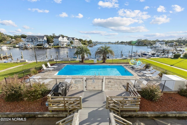 view of pool with a lawn, a water view, and a patio area