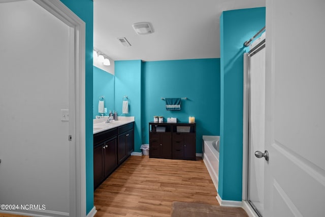 bathroom featuring vanity, hardwood / wood-style floors, and a tub to relax in