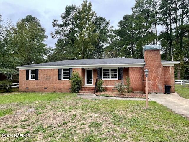 single story home featuring a front yard, driveway, a chimney, crawl space, and brick siding