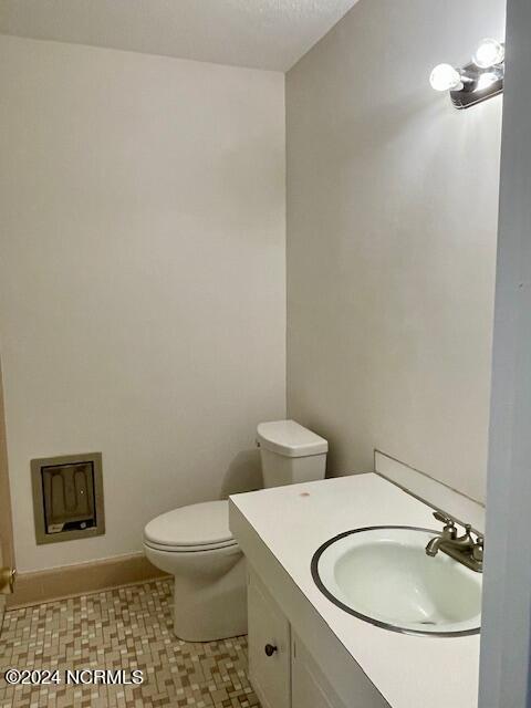 bathroom with toilet, vanity, and baseboards