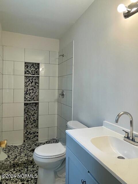 bathroom with vanity, toilet, and tiled shower