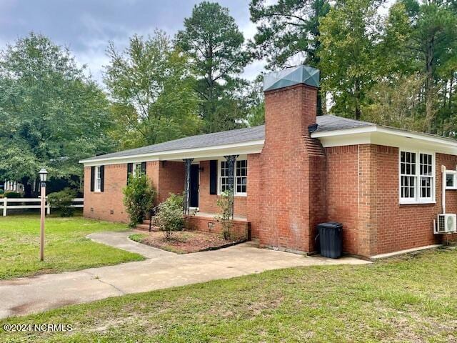 single story home with brick siding, a chimney, a front yard, and fence