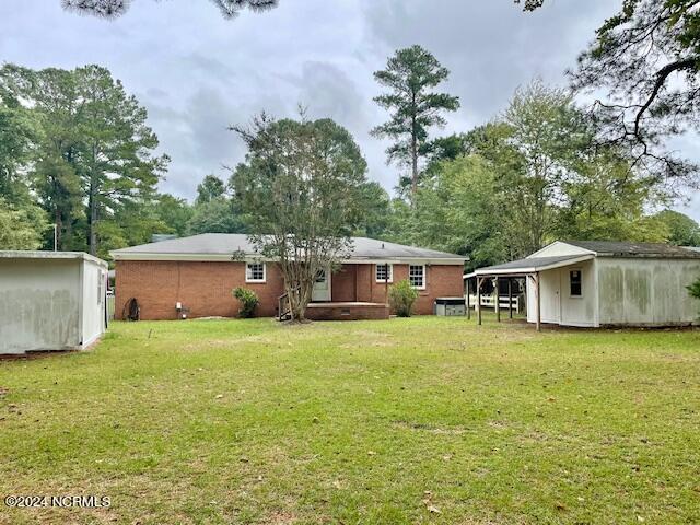 back of house with an outdoor structure and a yard