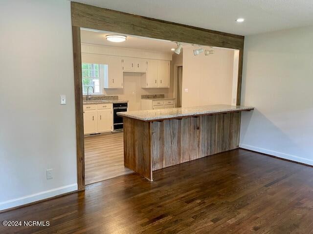 kitchen with white cabinetry, oven, dark hardwood / wood-style floors, and sink