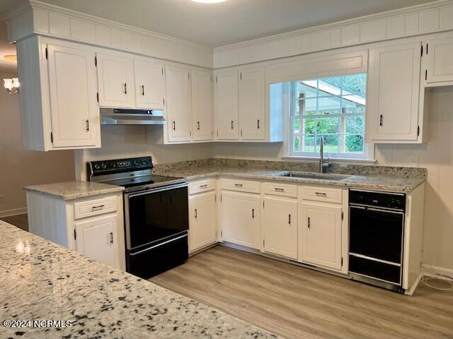 kitchen featuring light hardwood / wood-style floors, sink, white cabinets, light stone countertops, and black range with electric cooktop