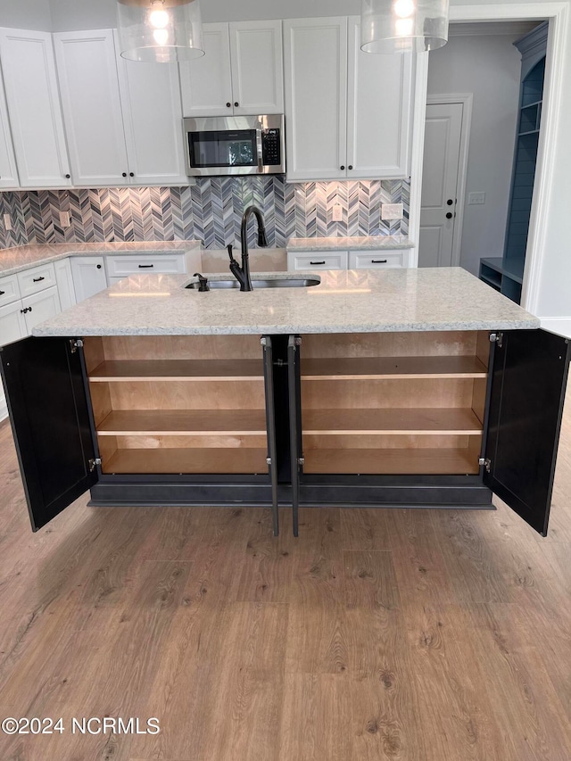 kitchen featuring light stone counters, white cabinets, a center island, hardwood / wood-style floors, and sink