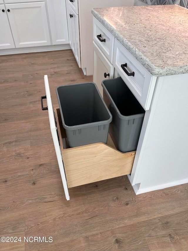 interior details featuring light stone countertops, hardwood / wood-style floors, and white cabinetry