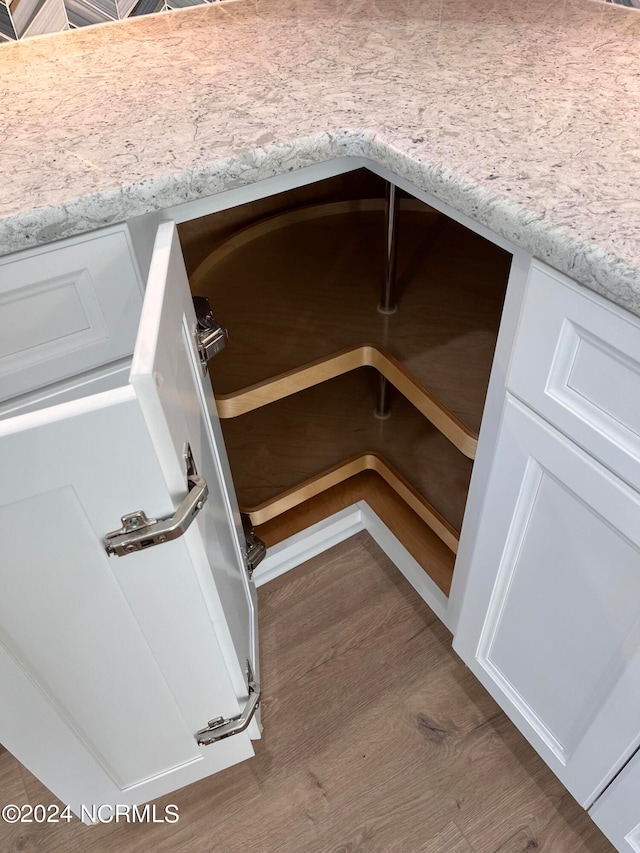 interior details with light stone countertops, dark wood-type flooring, and white cabinetry