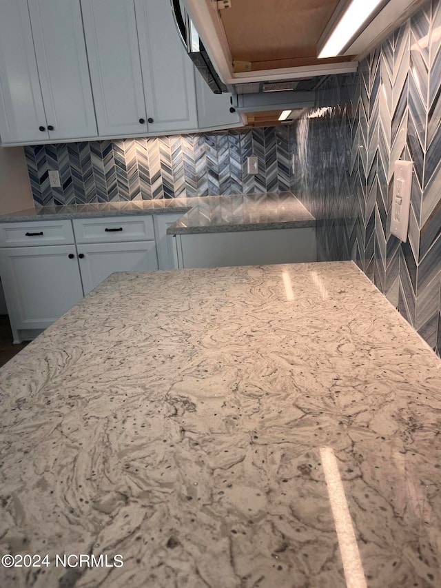 kitchen featuring backsplash, light stone counters, and white cabinets