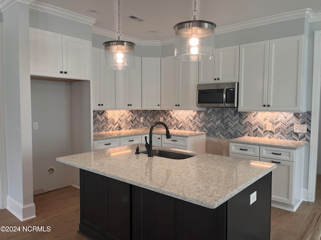 kitchen featuring light hardwood / wood-style flooring, a center island with sink, hanging light fixtures, and sink