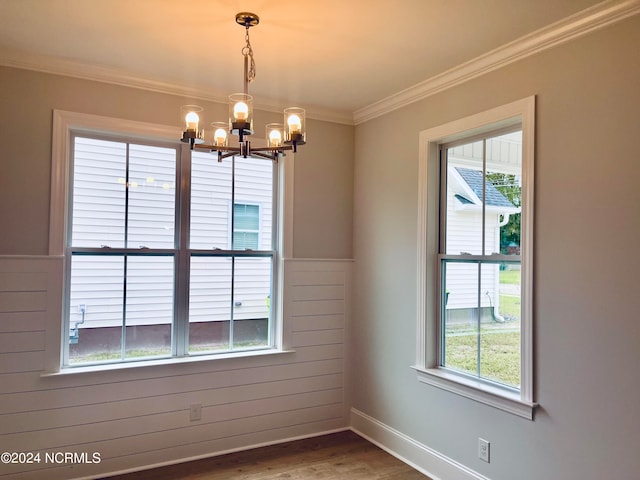 empty room with ornamental molding, wood-type flooring, a chandelier, and wood walls