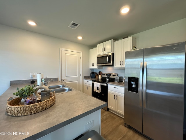 kitchen featuring appliances with stainless steel finishes, sink, dark hardwood / wood-style flooring, and white cabinetry