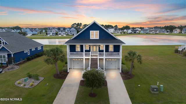 view of front of house with a lawn, a water view, a porch, and a garage