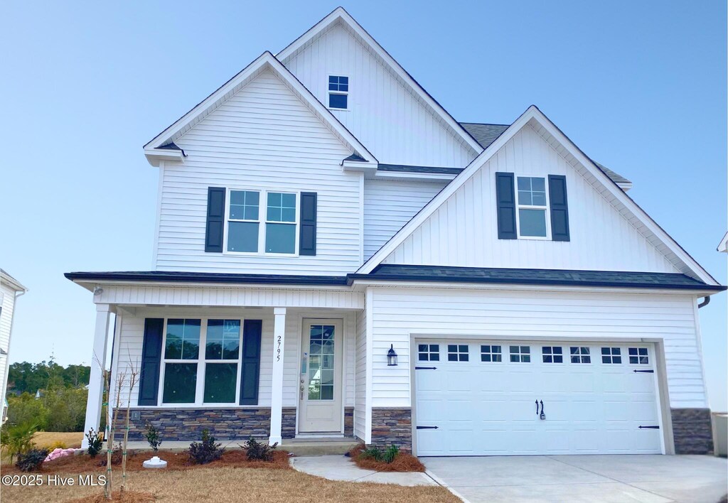 2795 Longleaf Pine Cir, Leland, NC 28451 - view of front of house with a porch, concrete driveway, a garage, stone siding, and board and batten siding